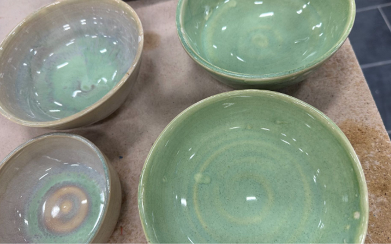 Four green ceramic bowls that are laid out in a square shape, with each bowl at one corner. 