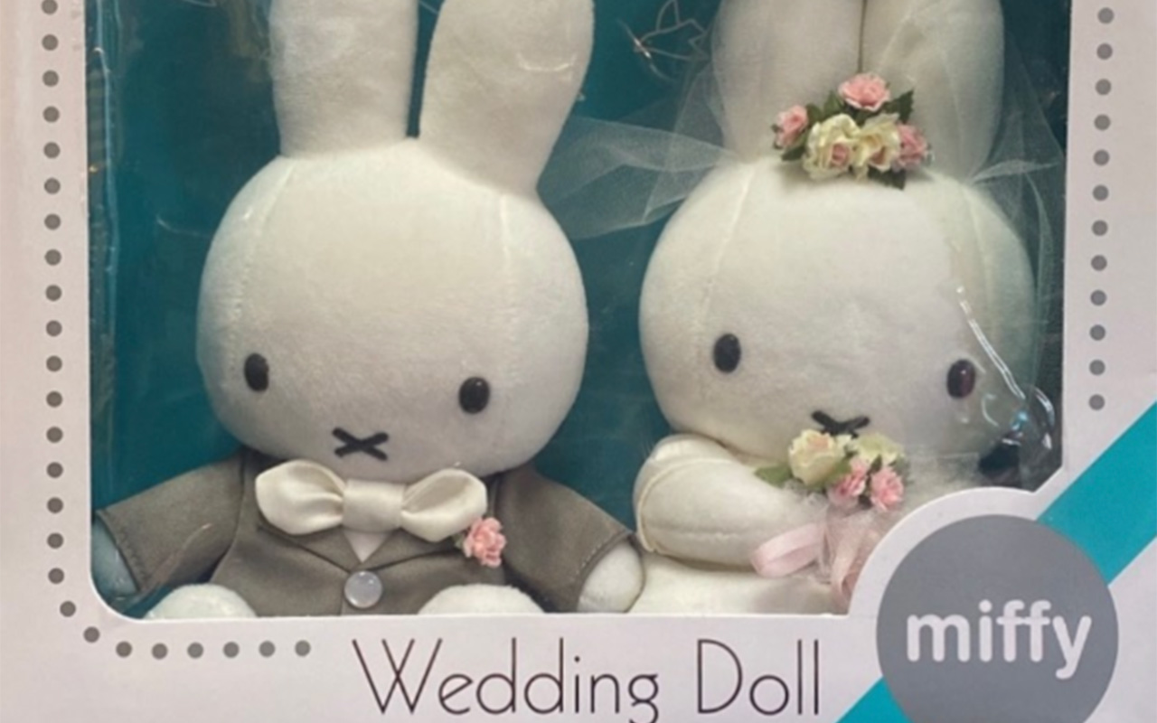 Bunny wedding dolls named miff in a plastic container. The bride has flowers in her hand and hair. The groom has a gray tuxedo on.